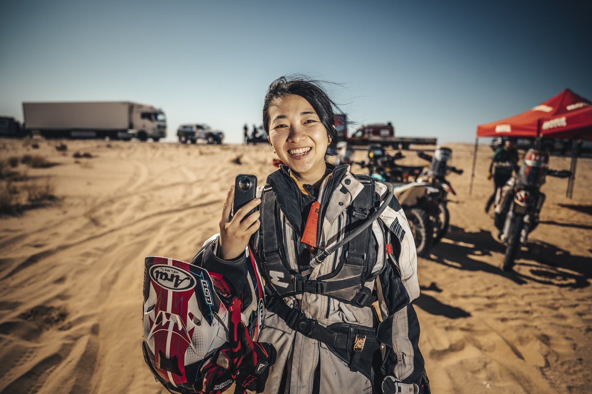 Girl with jacket and helmet in front of rally raid mpotorbikes